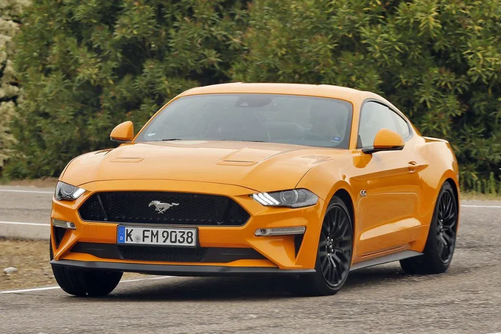 Ein Ford Mustang GT Coupé der aktuellen Generation auf einer Straße mit sichtbarem V8-Motorraum und installiertem Kompressor